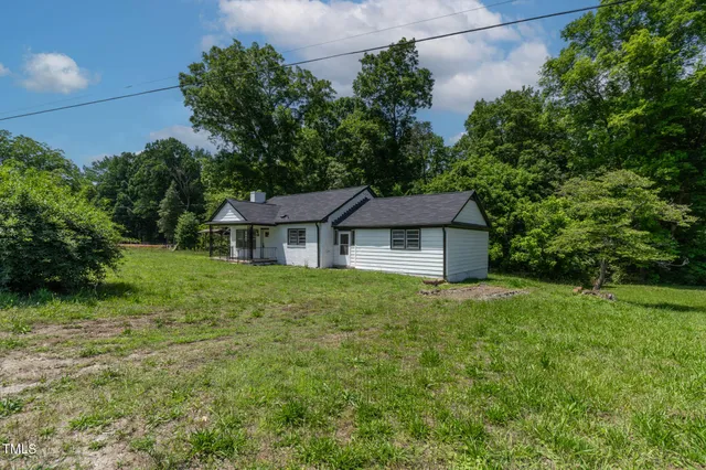 a view of a house with a big yard potted plants and large tree