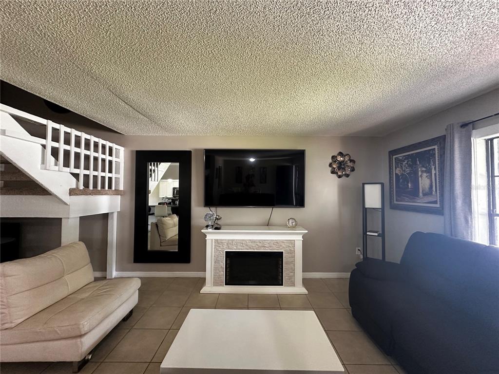 5434 Saddlebrook Way, Unit 3 Wesley Chapel, FL 33543 - Photo 6 of 17 a living room with furniture a flat screen tv and a fireplace