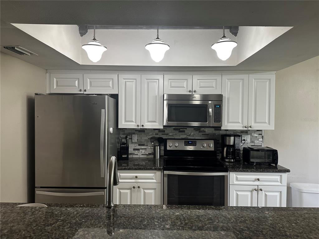 5434 Saddlebrook Way, Unit 3 Wesley Chapel, FL 33543 - Photo 8 of 17 a kitchen with stainless steel appliances granite countertop a refrigerator and a stove top oven