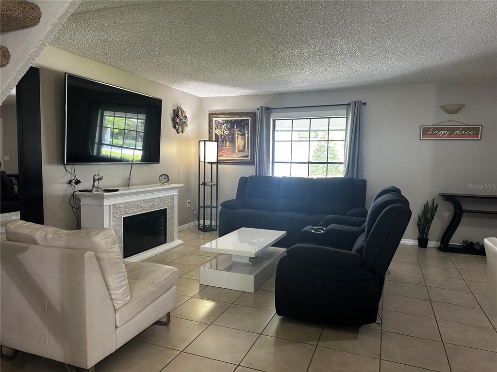 5434 Saddlebrook Way, Unit 3 Wesley Chapel, FL 33543 - Photo 10 of 17 a living room with furniture a flat screen tv and a fireplace
