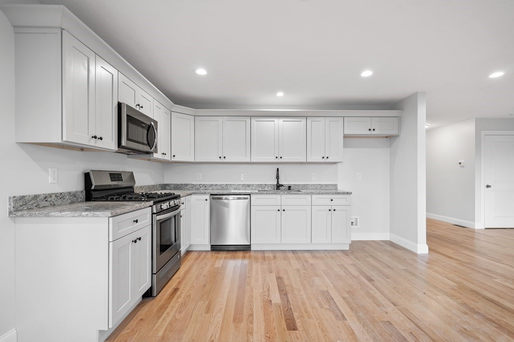 108 High Street, Unit B Wareham, MA 02571 - Photo 13 of 31 a kitchen with stainless steel appliances granite countertop a stove a sink and white cabinets