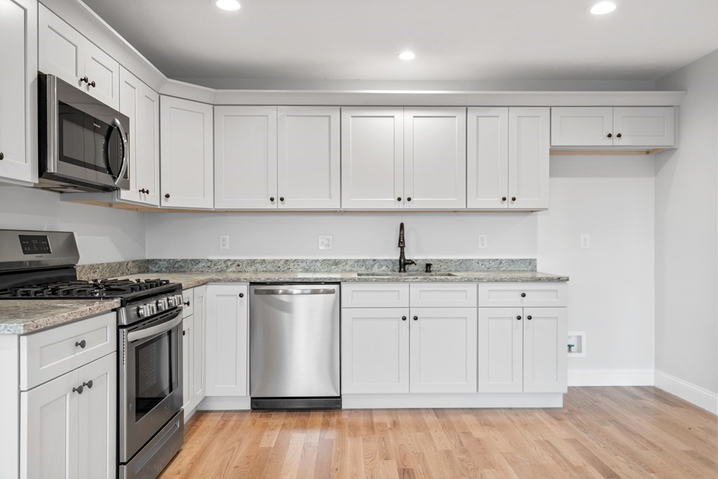 108 High Street, Unit B Wareham, MA 02571 - Photo 14 of 31 a kitchen with granite countertop white cabinets and stainless steel appliances