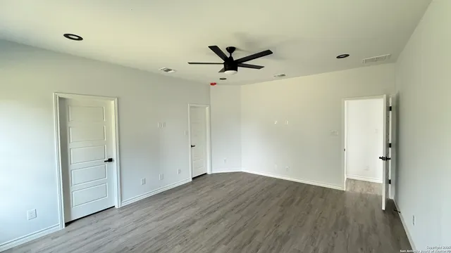 an empty room with wooden floor and a ceiling fan