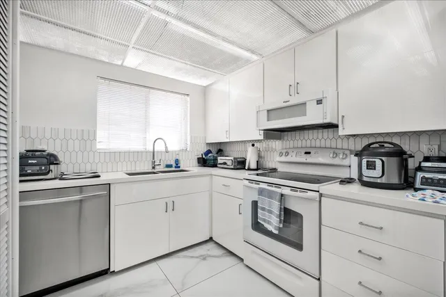 a kitchen with cabinets appliances a sink and a window