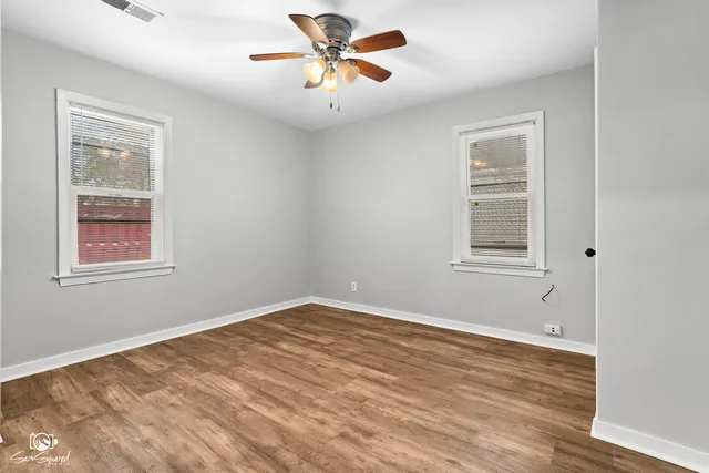 a view of a big room with wooden floor and windows