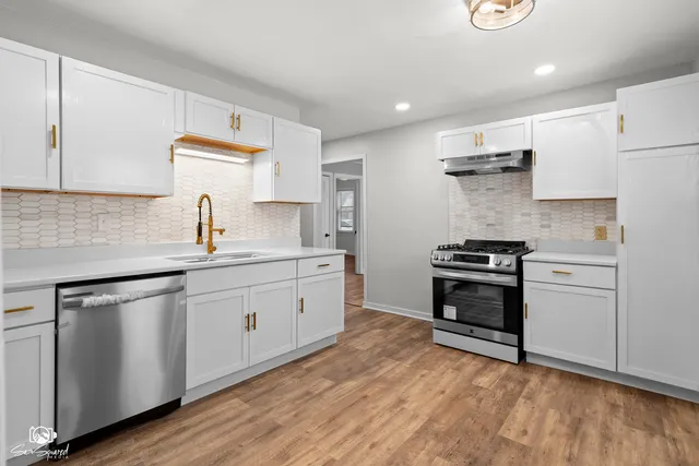 a kitchen with stainless steel appliances a sink cabinets and wooden floor