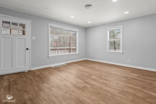 an empty room with wooden floor and windows