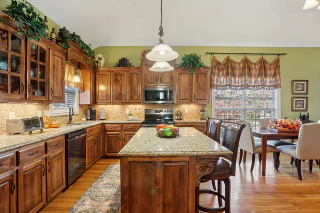 a kitchen with granite countertop a stove cabinets and dining table with wooden floor