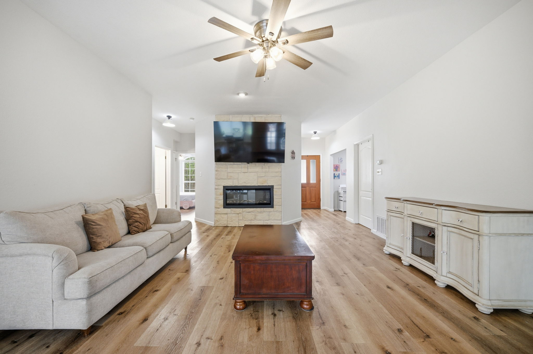9024 Heiden Lane Austin, TX 78749 - Photo 7 of 28 Open-concept living space featuring wood-finish flooring, a stone-clad fireplace with a built-in electric insert, and a ceiling fan with integrated lighting