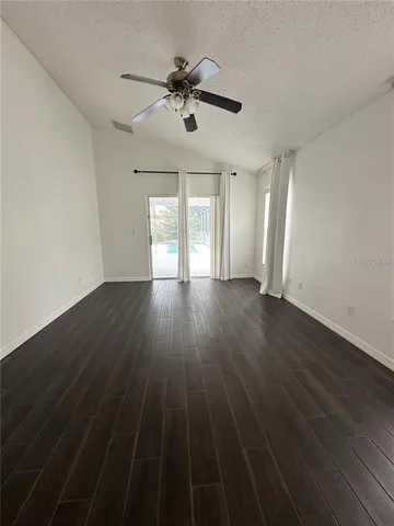 a view of an empty room with wooden floor and a ceiling fan