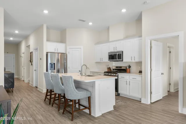 a kitchen with stainless steel appliances a white table chairs refrigerator and a stove top oven