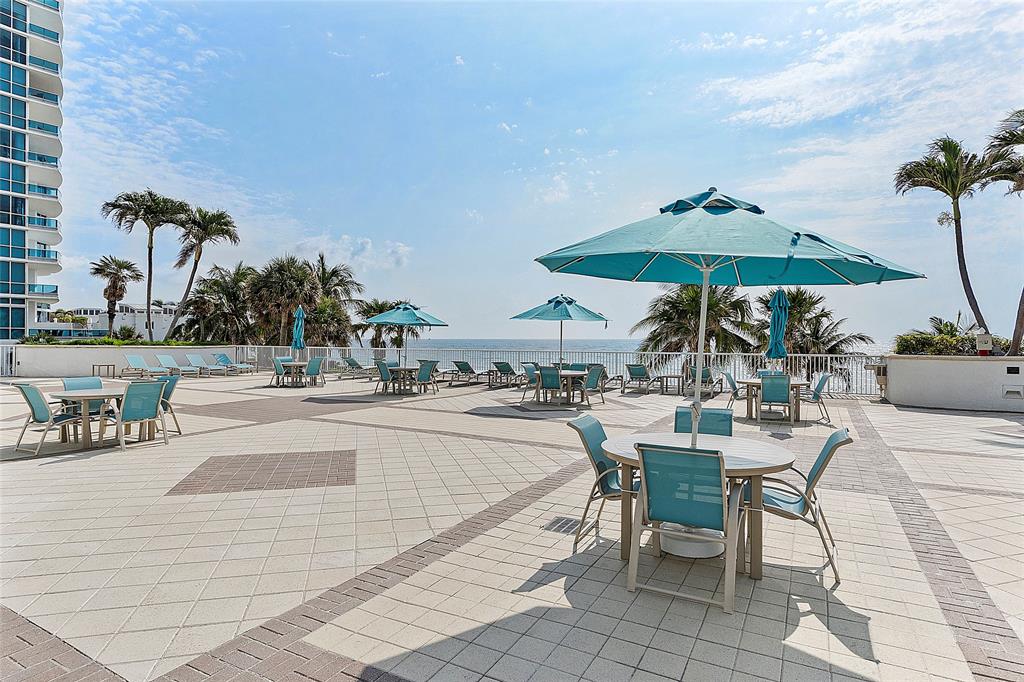 1620 South Ocean Boulevard, Unit 15J Lauderdale-by-the-Sea, FL 33062 - Photo 26 of 28 a view of a patio with chairs and table under an umbrella