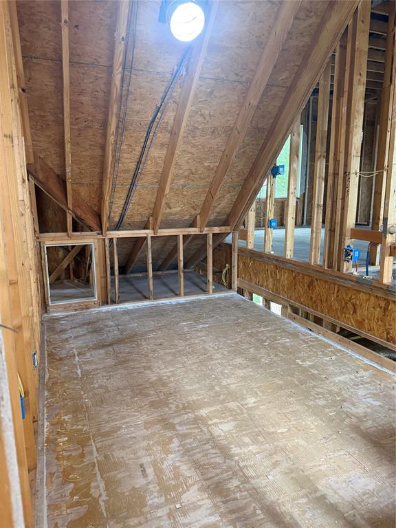 83 Bass Road Pottsboro, TX 75076 - Photo 11 of 31 Unfinished room featuring exposed wood framing, plywood subfloor, and a sloped ceiling with an overhead light fixture
