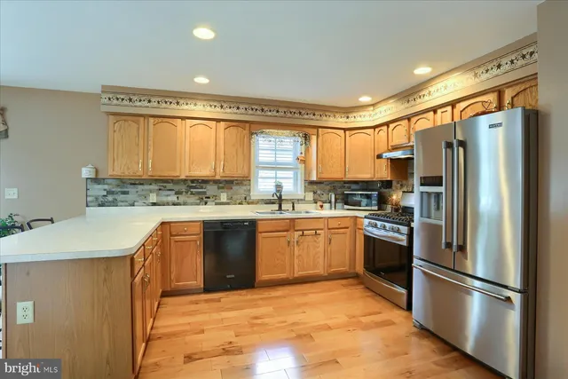 a kitchen with stainless steel appliances granite countertop a refrigerator a sink dishwasher a stove top oven a refrigerator and cabinets