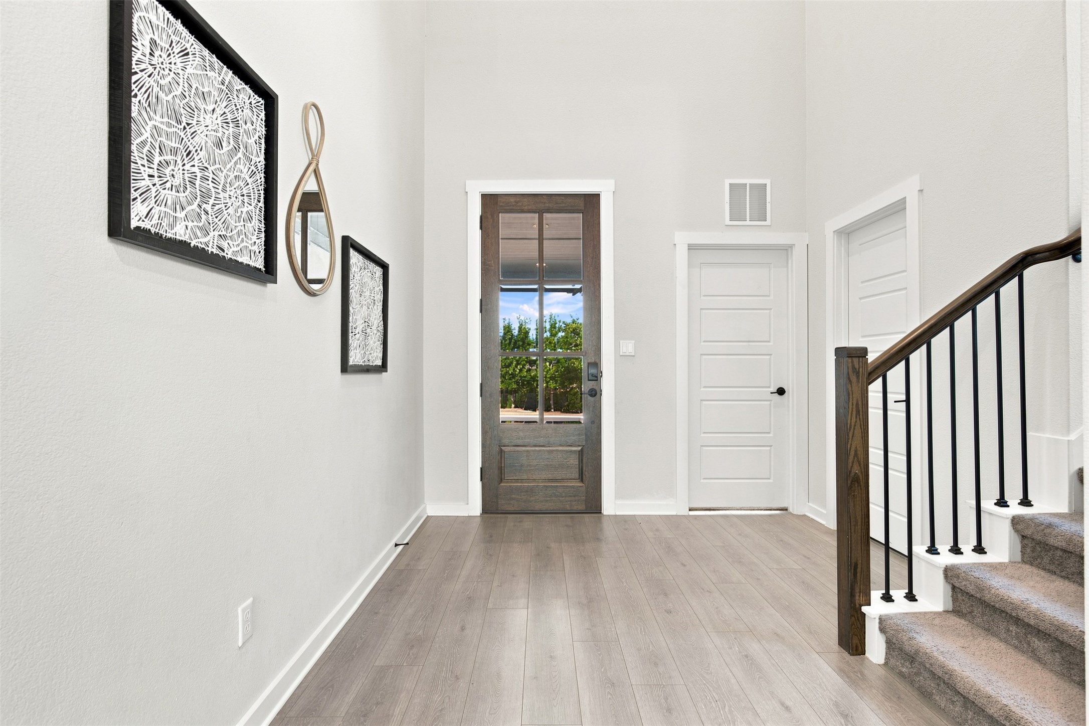 An inviting entrance foyer reveals soaring ceilings, durable wood-look flooring, and a handsome staircase.