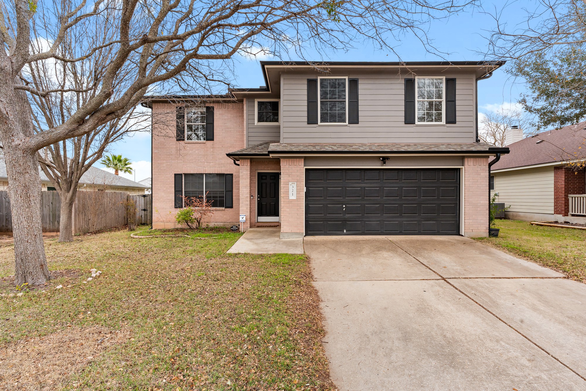 Traditional-style home featuring an attached garage, concrete driveway, and brick siding