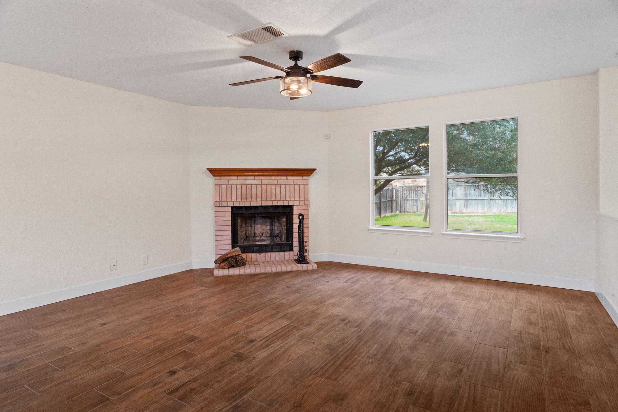 321 Nicole Way Bastrop, TX 78602 - Photo 4 of 32 Unfurnished living room featuring a brick fireplace, dark wood-style floors, and ceiling fan