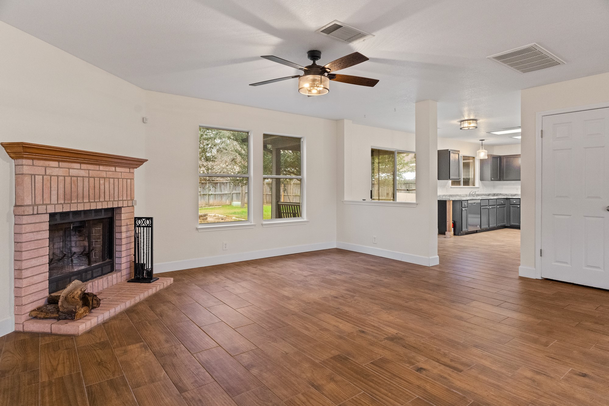 321 Nicole Way Bastrop, TX 78602 - Photo 6 of 32 Unfurnished living room with dark wood-style floors, a fireplace, and ceiling fan