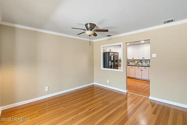 a view of an empty room with window and wooden floor