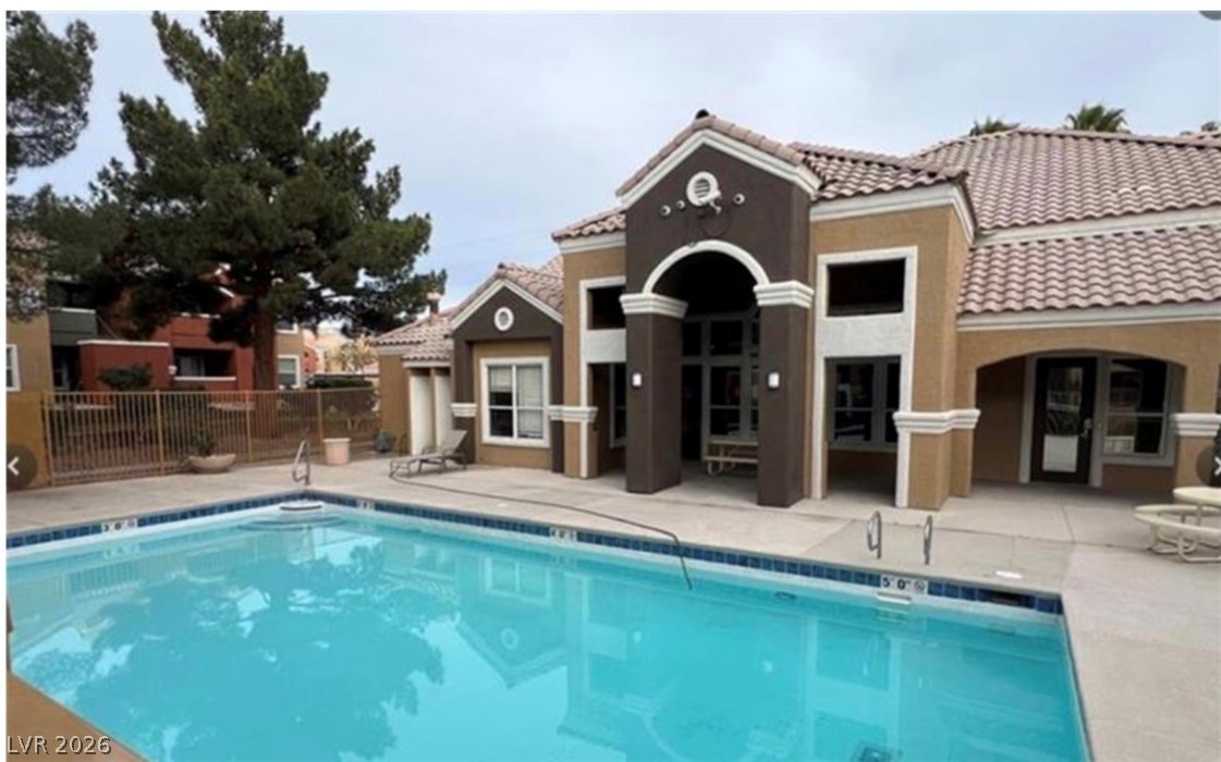 8101 West Flamingo Road, Unit 2129 Las Vegas, NV 89147 - Photo 11 of 12 A sparkling pool invites relaxation, set against a charming clubhouse with Mediterranean-inspired architecture.
