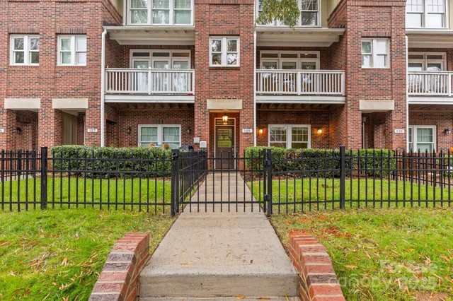 a view of a brick house with a yard and plants