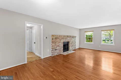 an empty room with windows fireplace and wooden floor