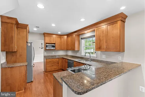a kitchen with stainless steel appliances granite countertop a sink a refrigerator and a granite counter tops with a large window