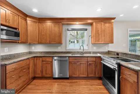 a kitchen with stainless steel appliances granite countertop wooden cabinets and a stove top oven