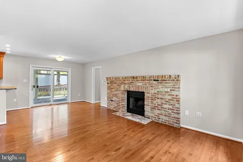 an empty room with wooden floor fireplace and windows