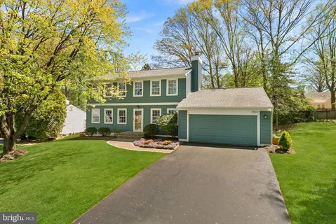 a front view of a house with garden and trees