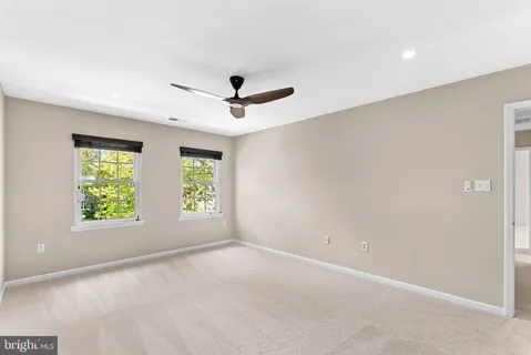 an empty room with windows and ceiling fan