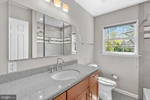 a bathroom with a granite countertop sink toilet and shower