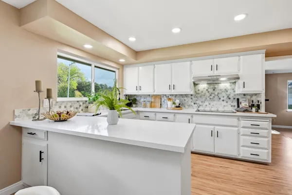 a kitchen with stainless steel appliances kitchen island wooden floors and white cabinets