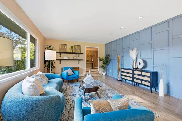 a living room with furniture kitchen view and a large window