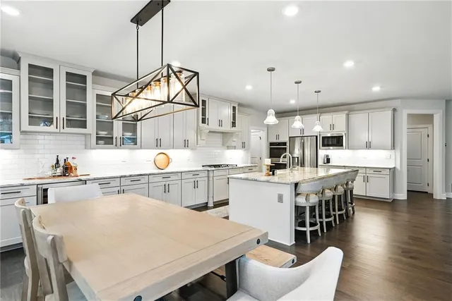 a kitchen with stainless steel appliances a stove a sink a kitchen island with a dining table and chairs