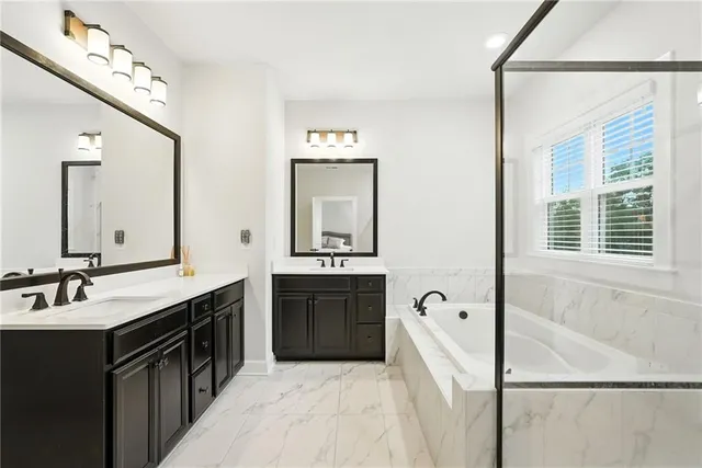 a spacious bathroom with a double vanity sink a mirror and a bathtub