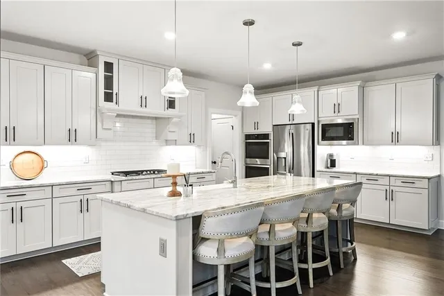 a kitchen with stainless steel appliances granite countertop a sink a stove a refrigerator cabinets and chairs