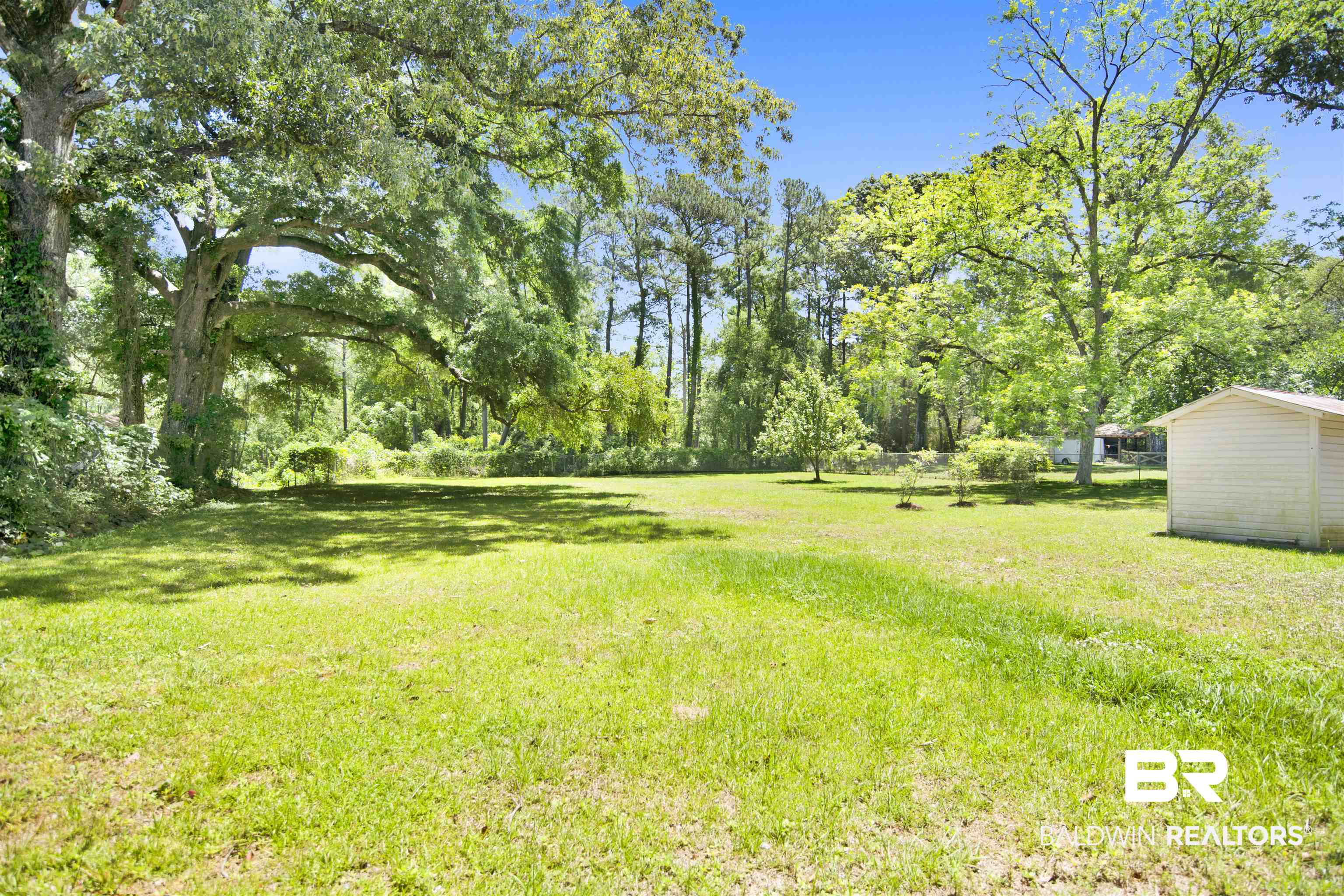 30888 Cemetery Road Daphne, AL 36527 - Photo 31 of 36 Expansive green lawn with mature trees and a detached white storage shed