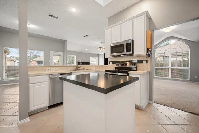 a kitchen with stainless steel appliances a sink dishwasher stove and white cabinets