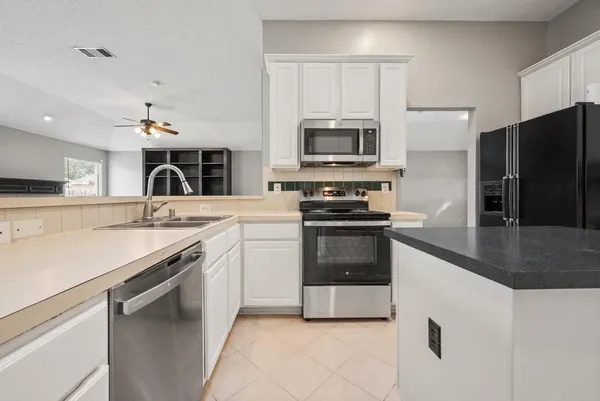 a kitchen with stainless steel appliances granite countertop a stove top oven a sink a counter space and cabinets