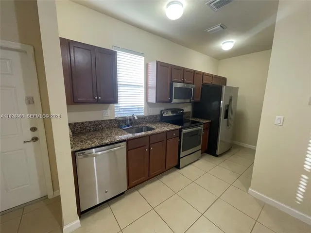 a kitchen with stainless steel appliances granite countertop a stove a sink and a refrigerator