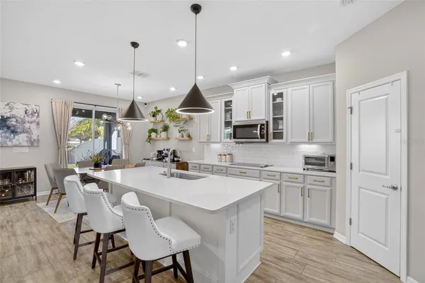 a kitchen with stainless steel appliances kitchen island granite countertop a dining table chairs and white cabinets
