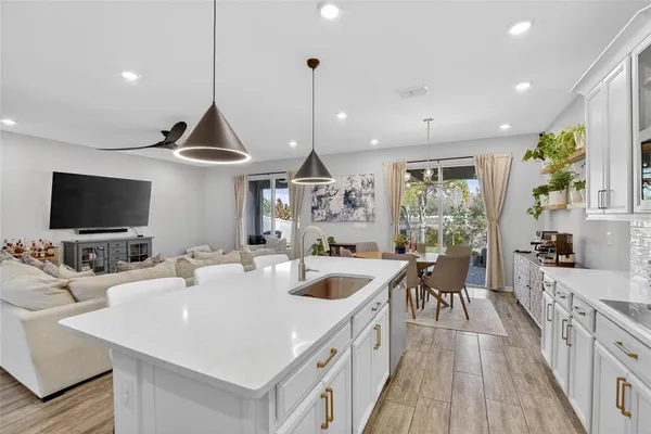 a large kitchen with kitchen island a stove a sink a refrigerator and a wooden floor