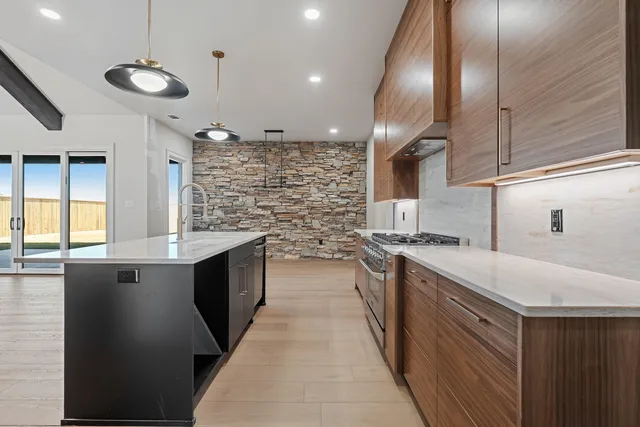 a large kitchen with stainless steel appliances granite countertop a sink a stove and a refrigerator