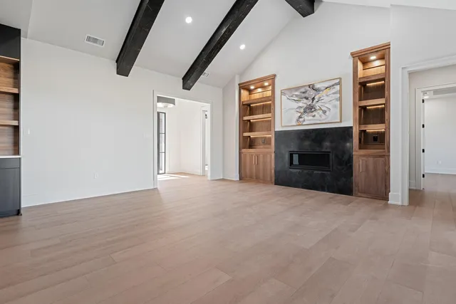 an empty room with wooden floor cabinet and windows