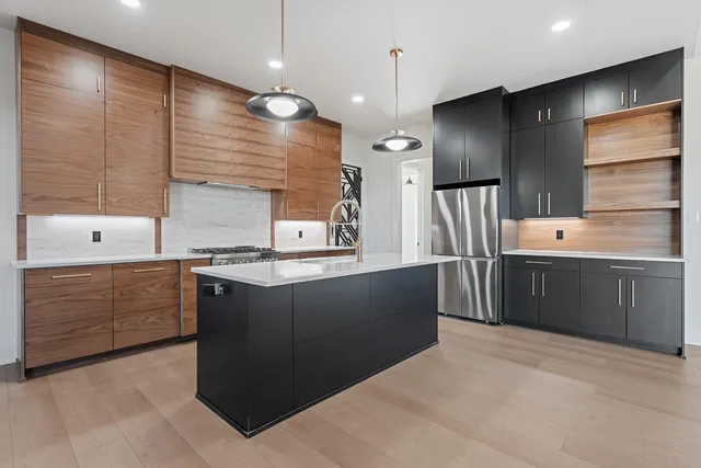 a large kitchen with stainless steel appliances kitchen island granite countertop a stove a sink dishwasher and a refrigerator