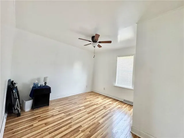 a view of a room with wooden floor and a ceiling fan