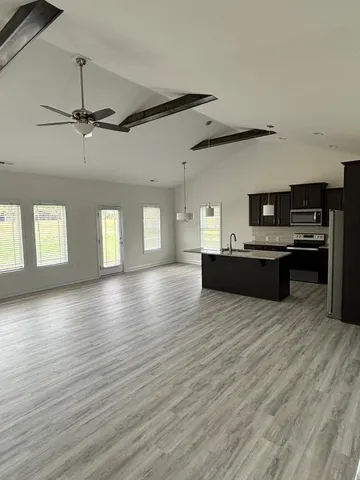 a view of a kitchen with kitchen island wooden floors and stainless steel appliances