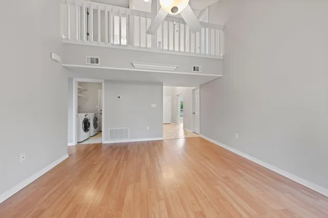 a view of an empty room with wooden floor fireplace and a window