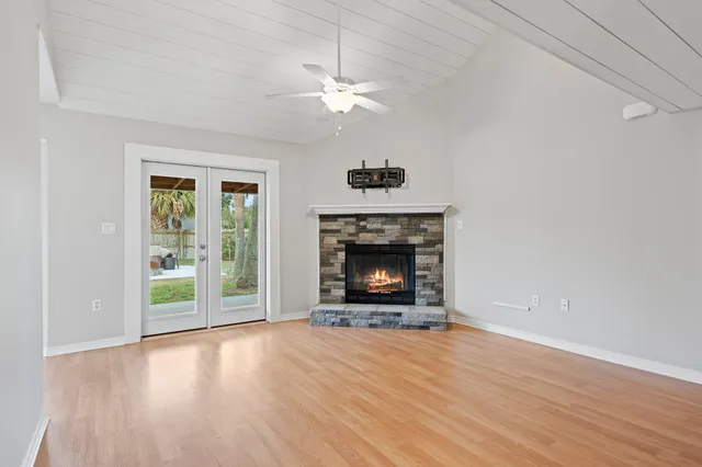 an empty room with wooden floor fireplace cabinet and windows